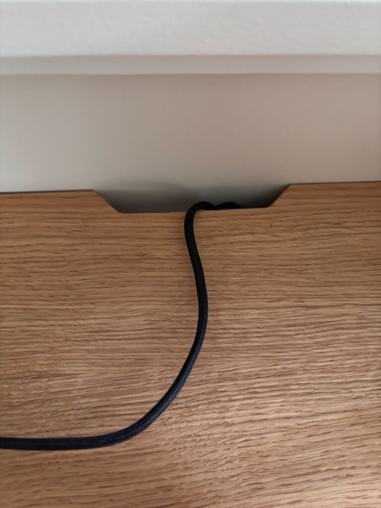 Passe-câble découpé dans un plateau en chêne massif avec fil noir