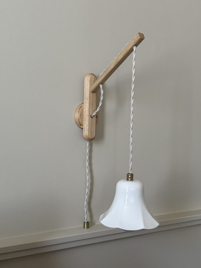 Liseuse en porcelaine blanche suspendue sur cordon torsadé, support mural en bois clair